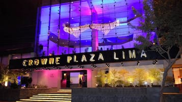 El exterior del hotel Crowne Plaza Lima, con señalización iluminada y un diseño arquitectónico moderno.