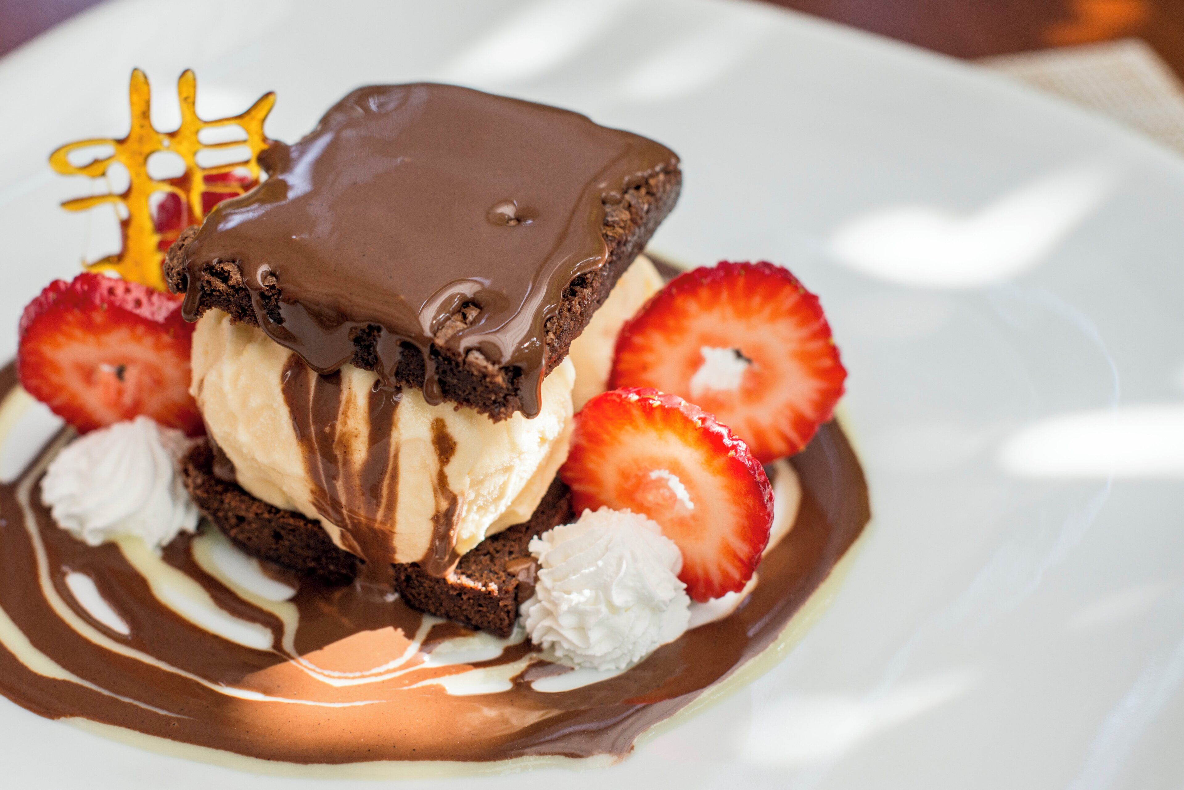 Un dessert composé de chocolat, de fraises et de crème fouettée, présenté dans une assiette.