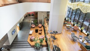 A modern interior with a central seating area, a staircase, and a view of the city. - Crowne Plaza Lima - Miraflores by IHG (Lima)