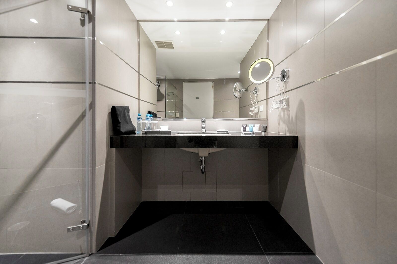 A modern bathroom with a glass shower enclosure, a vanity with a sink, and a mirror with a light.
