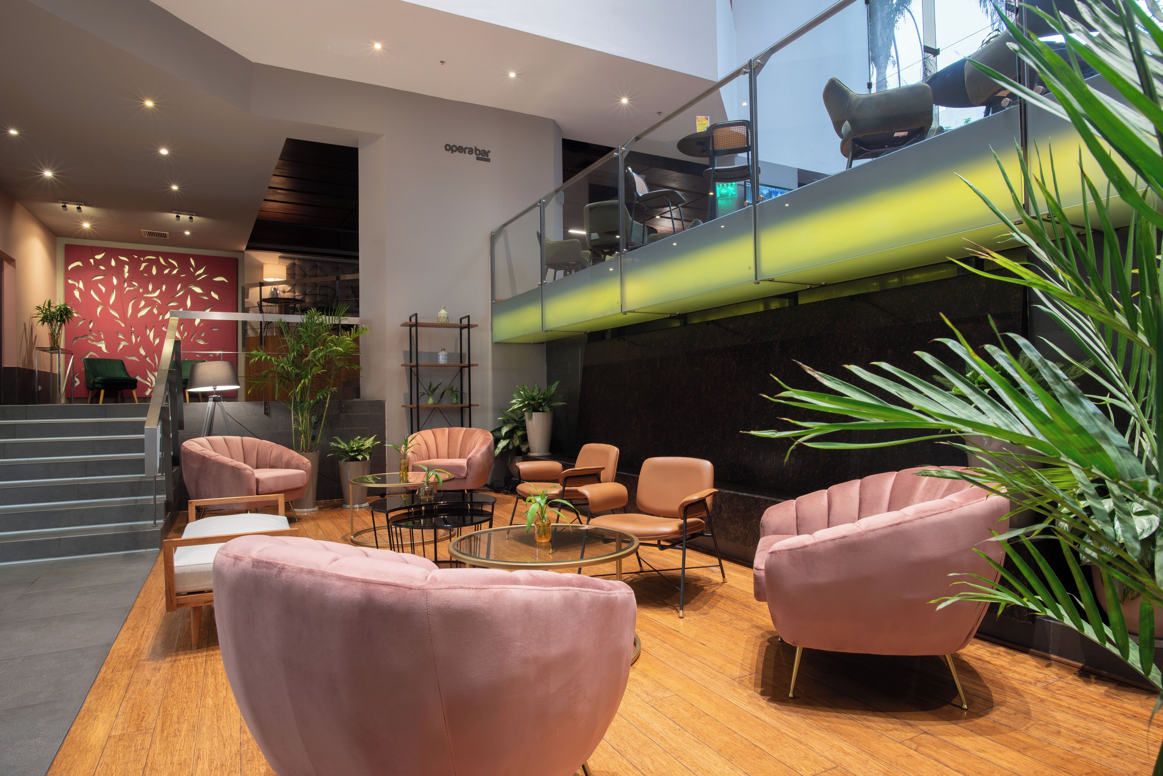 A modern lobby with a staircase, seating area, and a mezzanine level.