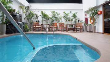 Una piscina al aire libre, sillones reclinables de piscina