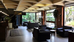 A spacious lobby with modern furniture, large windows, and a high ceiling with exposed beams. - Golf Tower Suites & Apartments (Buenos Aires)