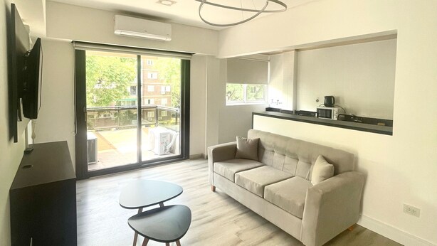 A modern living room with a sofa, a coffee table, and a TV mounted on the wall. - Golf Tower Suites & Apartments (Buenos Aires)