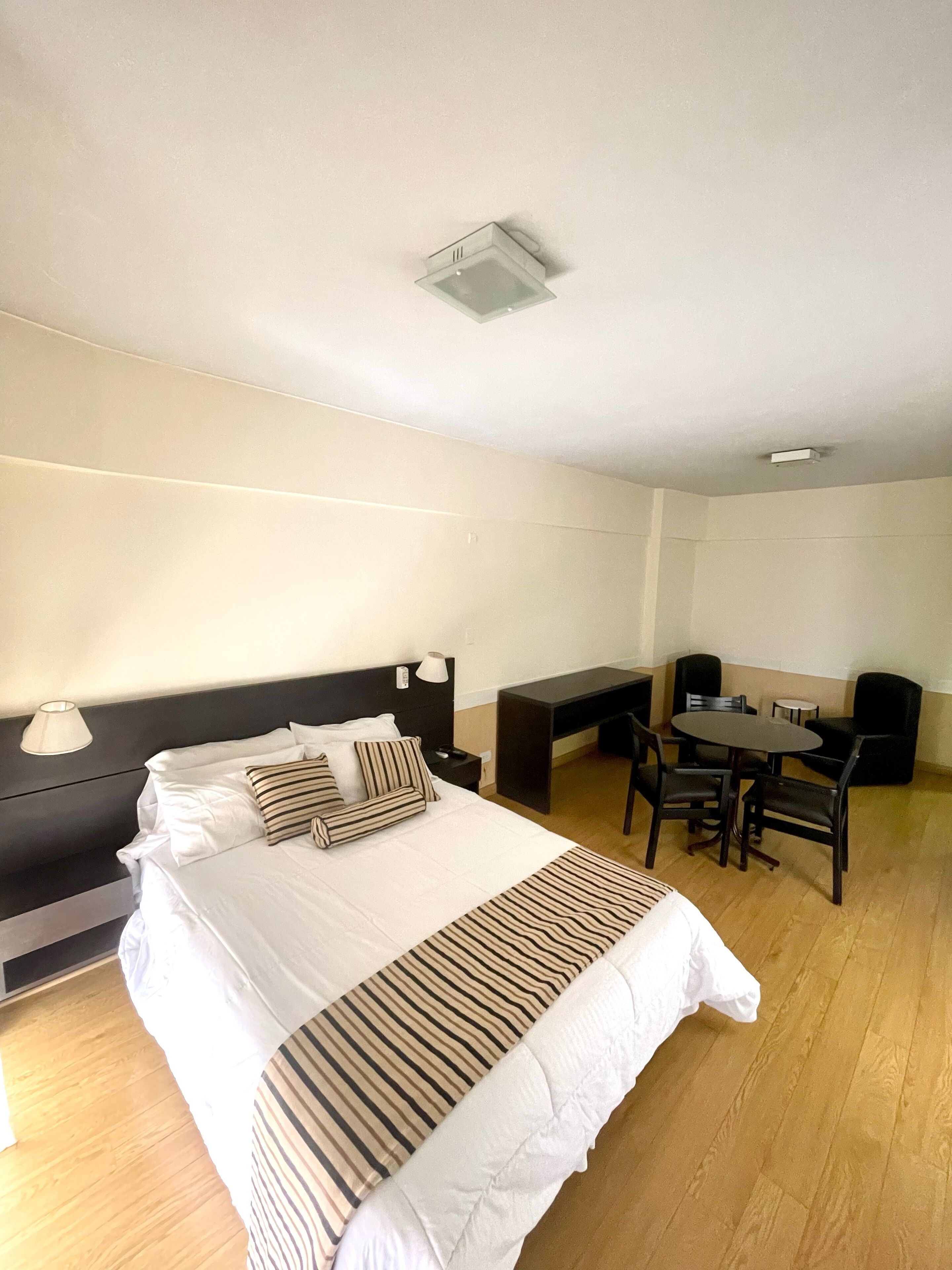 Ett hotellrum med en stor säng, sängbord, ett skrivbord och en stol.