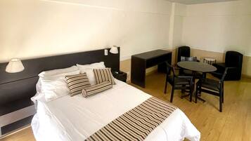 A hotel room with a large bed, bedside tables, a desk, and a chair.