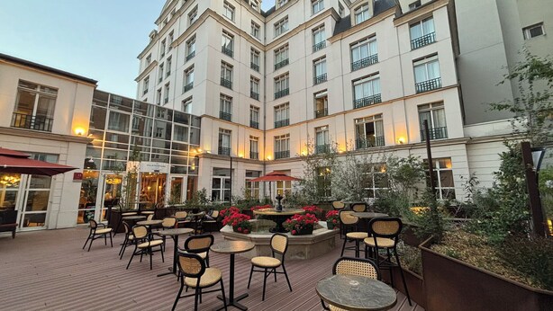 A courtyard with outdoor seating, a fountain, and a building with multiple floors and balconies. - Hôtel Vacances Bleues Villa Modigliani (Paris)