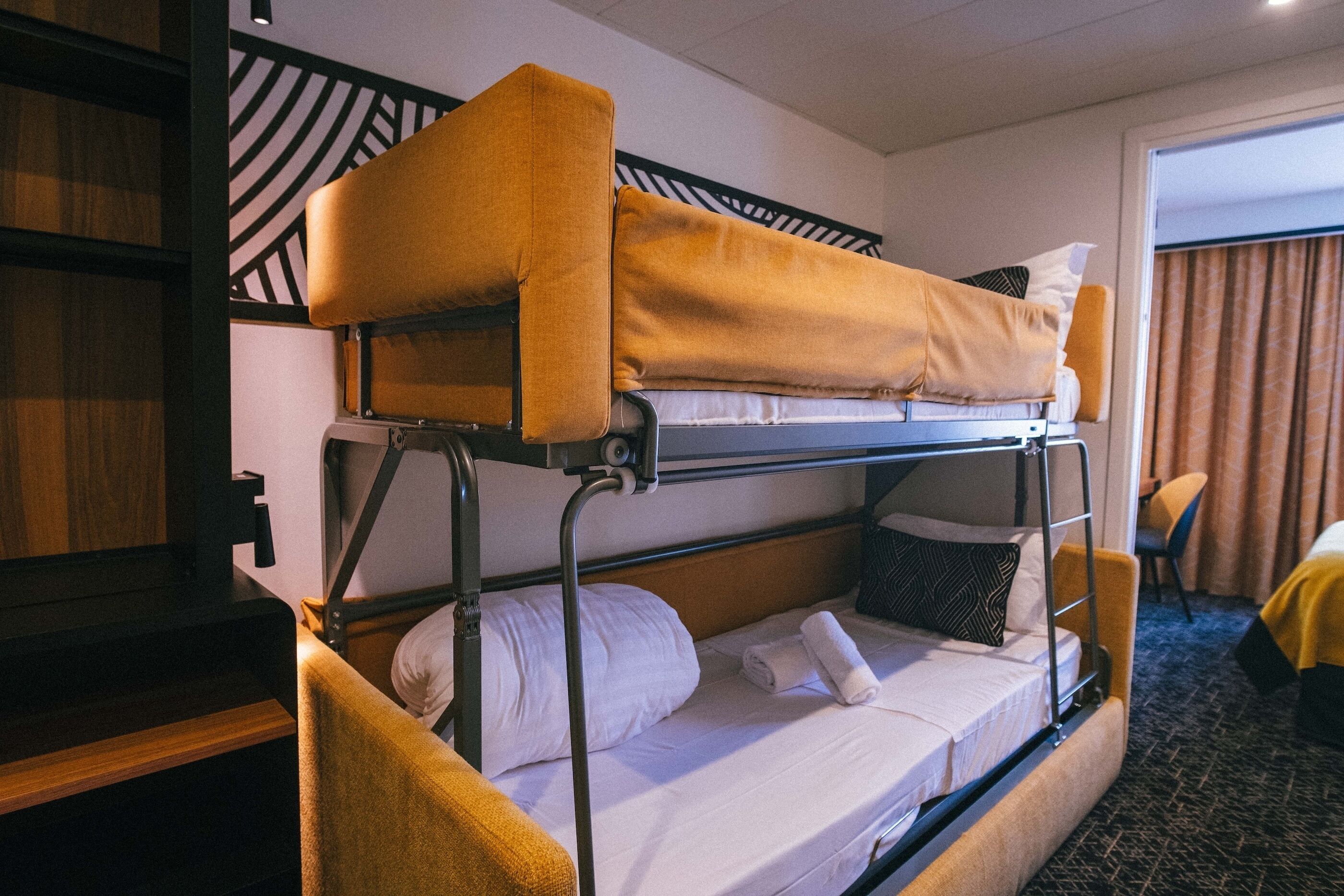A bunk bed room with a wooden headboard, a desk, and a chair.