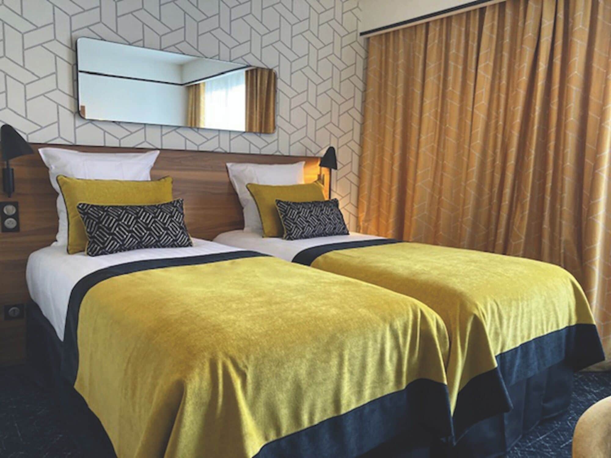 A hotel room with two beds, a mirror, and a patterned wall.