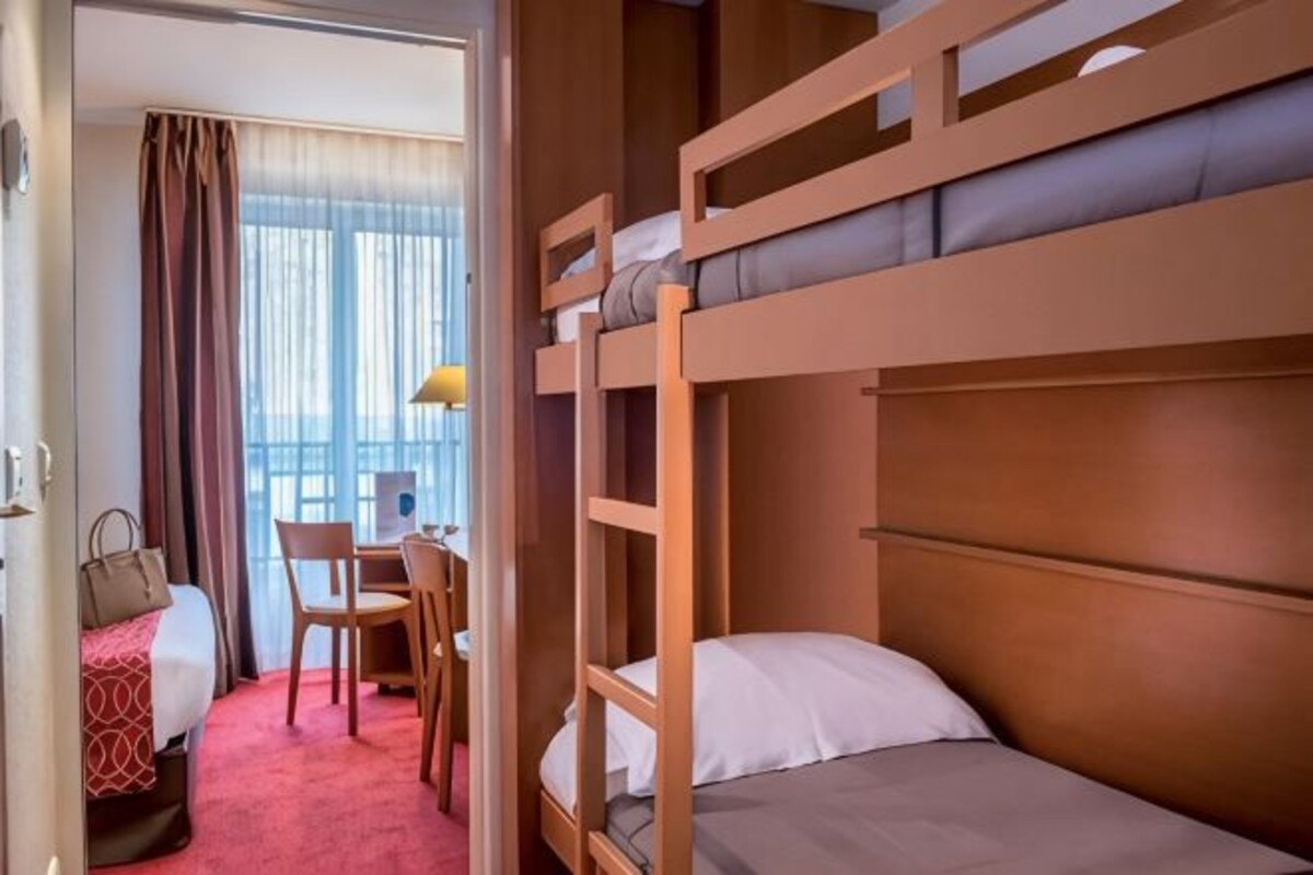 Habitación de hotel con literas, un escritorio, una silla y una cama.