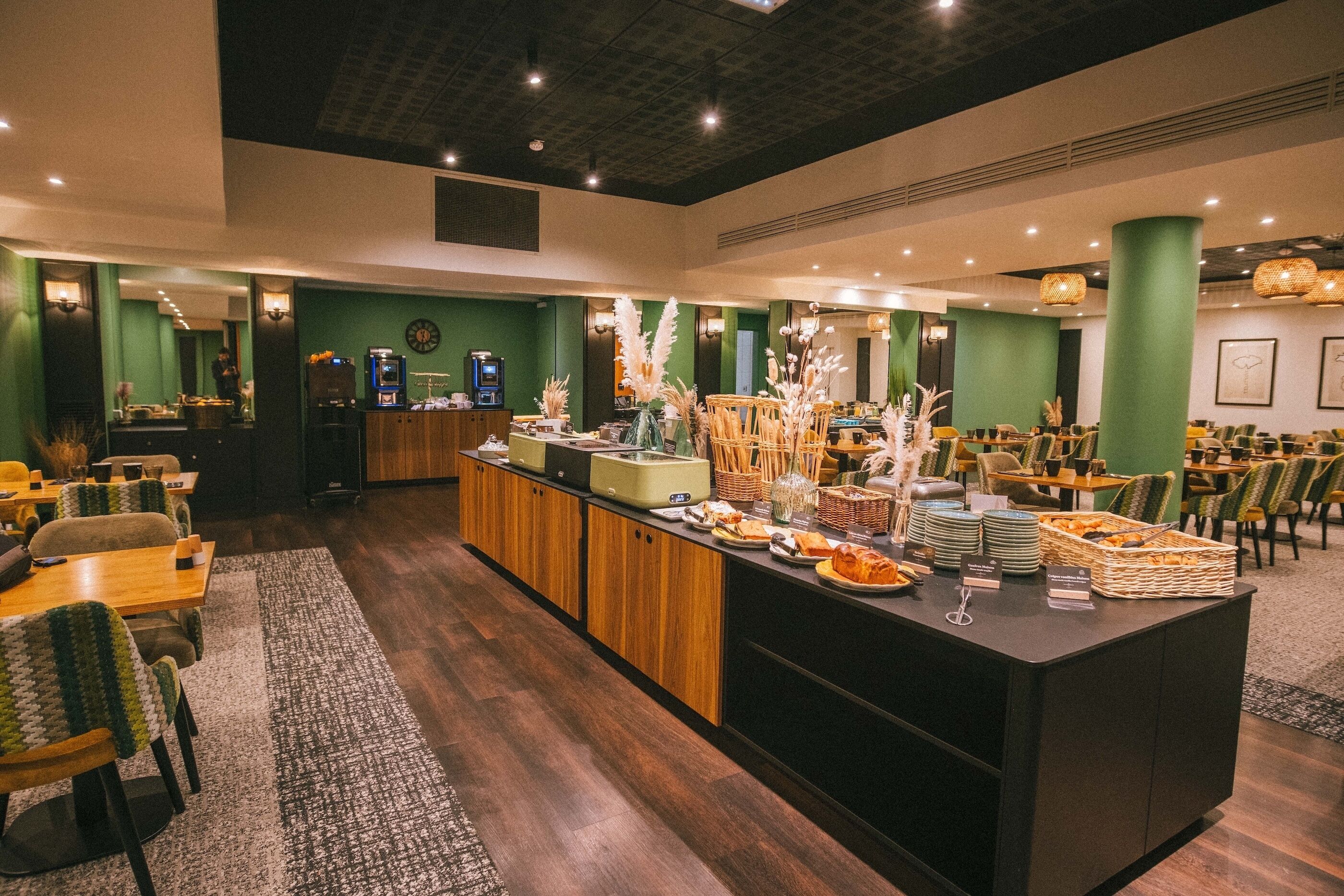 A restaurant with a buffet setup, wooden furniture, and green walls.