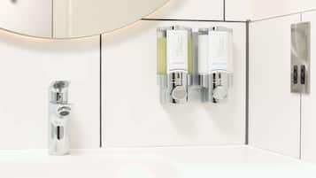Un baño moderno con un grifo cromado, un lavamanos blanco y dos dispensadores de jabón líquido con la etiqueta 'THERAPY WASH'.
