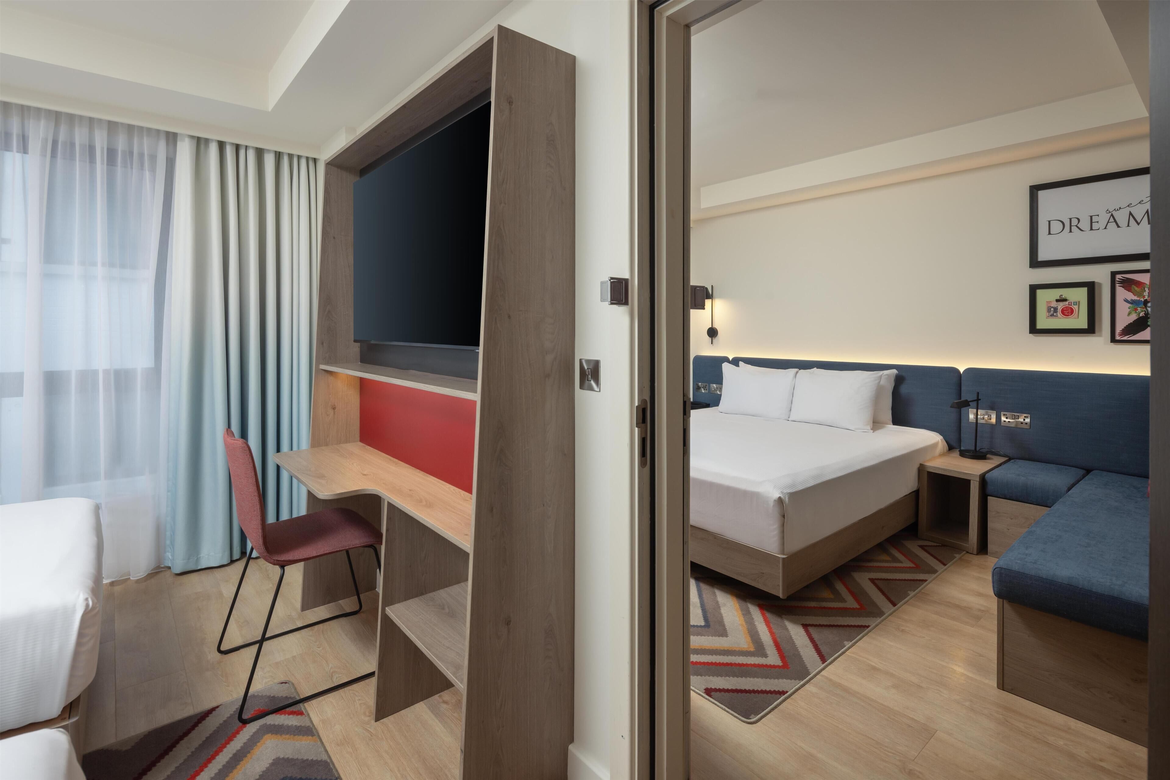 Une chambre d’hôtel équipée d’un lit, d’un bureau, d’une chaise, d’un canapé et d’une télévision.