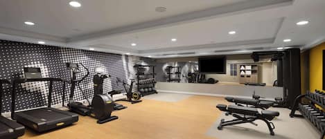 A modern gym with treadmills, elliptical machines, and weight benches.