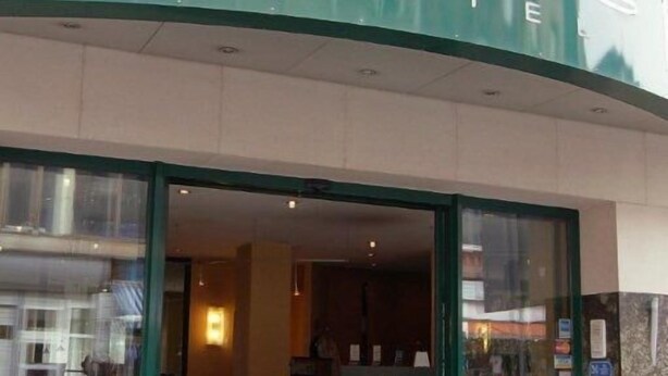 A hotel entrance with a reception desk and a glass door. - Memphis Hotel (Frankfurt)