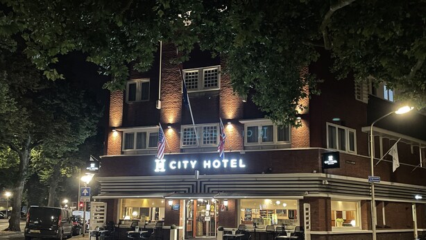 A CITY HOTEL with a brick facade, outdoor seating area, and a well-lit entrance.