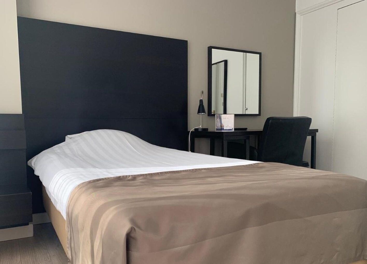 Ein Hotelzimmer mit Bett, Schreibtisch, Stuhl und Spiegel.