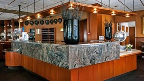 A reception area with a marble counter, wooden paneling, and a large vase with branches.