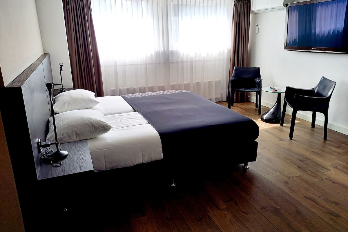 A hotel room with a bed, a desk, a chair, and a television.