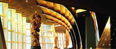 A modern interior with a curved staircase, a reception desk, and a large sculpture.