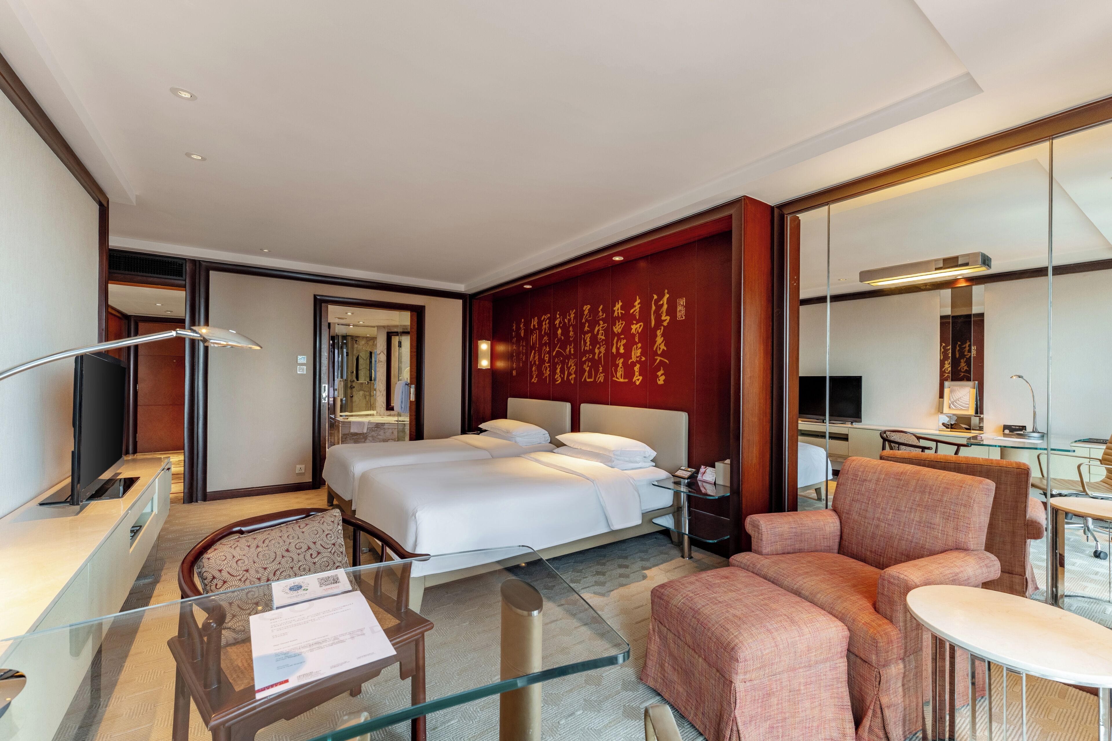 A hotel room with a bed, a desk, a chair, a sofa, and a TV.