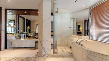 A modern bathroom with a glass-enclosed shower, a marble vanity, and a large bathtub.