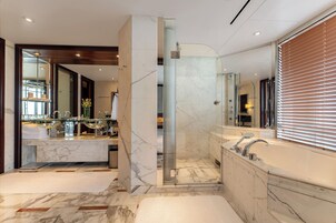 A modern bathroom with a glass-enclosed shower, a marble vanity, and a large bathtub.