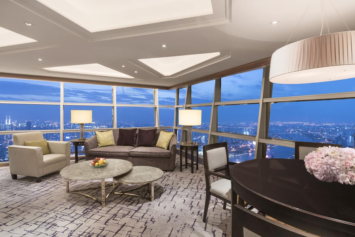 A spacious room with a city view, a piano, a sofa, and a dining table.