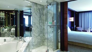Une salle de bain moderne avec une douche à parois de verre, un grand miroir et une baignoire.