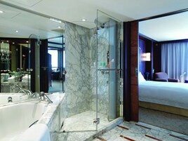 A modern bathroom with a glass-enclosed shower, a large mirror, and a bathtub.