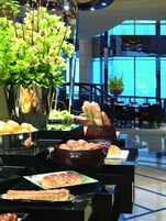 Een buffetgedeelte met diverse soorten eten, zoals fruit, brood en gebak, gepresenteerd op tafels.