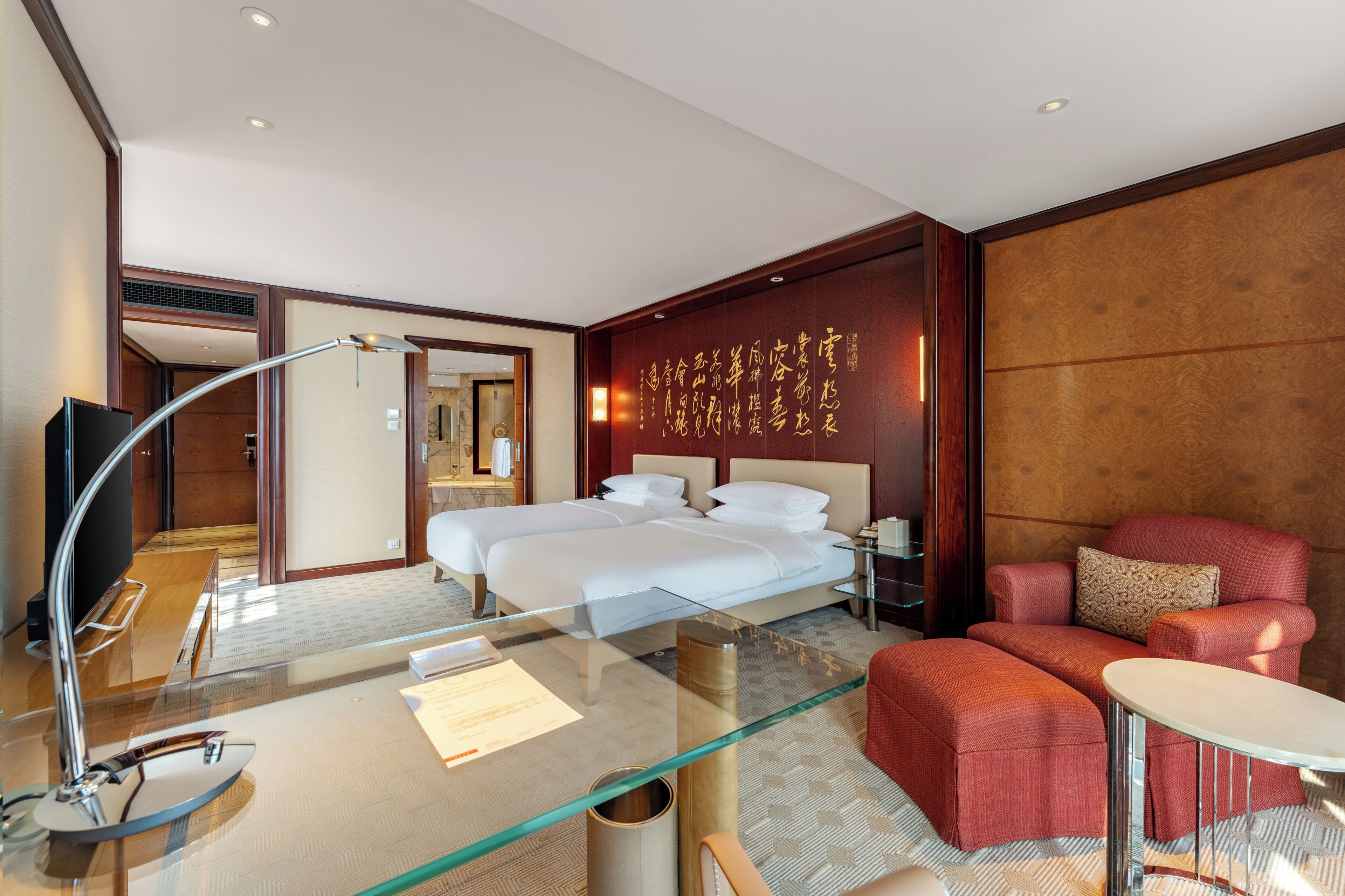 Ein Hotelzimmer mit einem großen Bett, einer Couch, einem Glastisch und einem Fernseher.