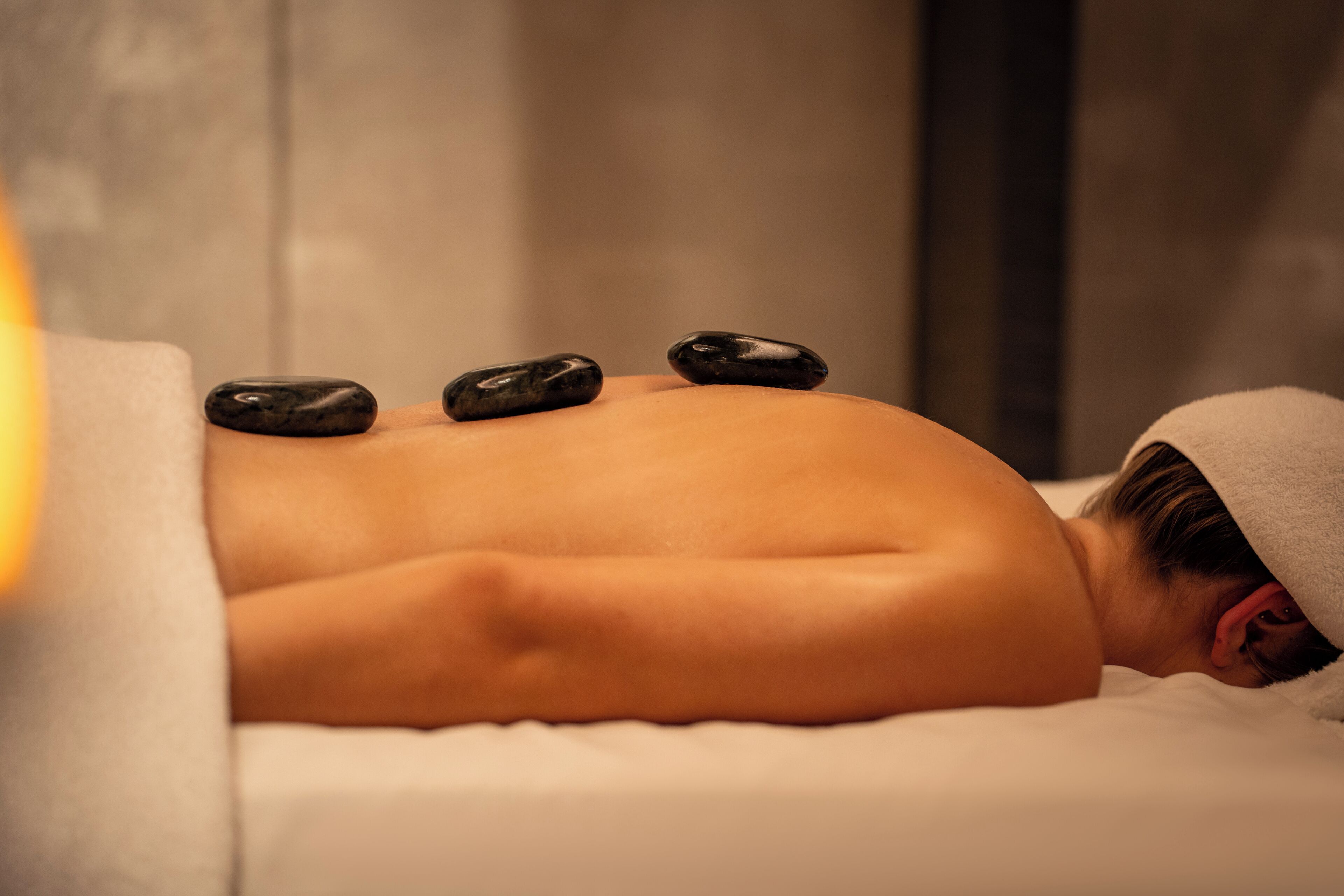A person receiving a stone massage on a bed.