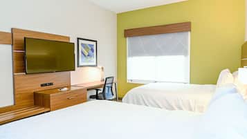 A hotel room with a bed, a desk with a chair, a television, and a window with blinds.