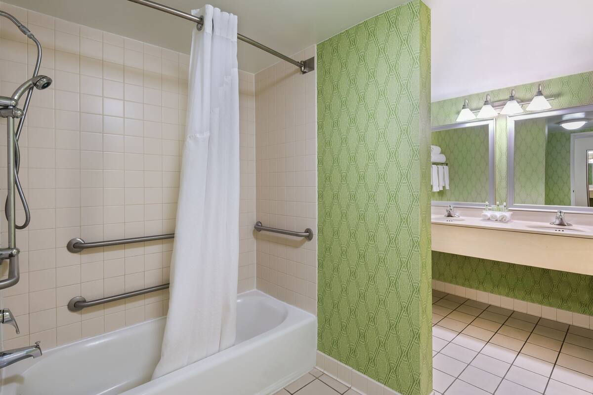 A bathroom with a bathtub, shower, and vanity with a mirror.