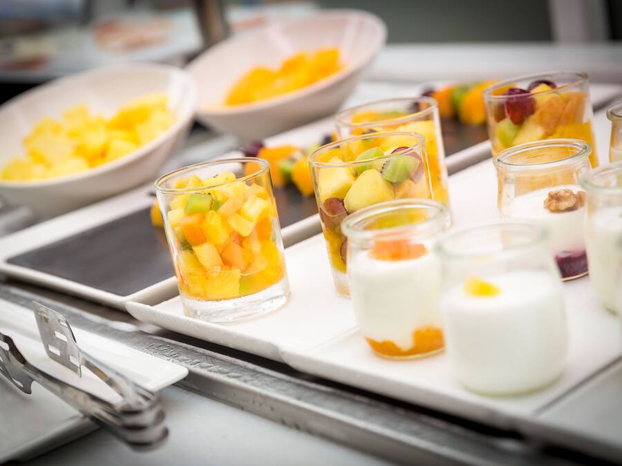 Ein Tablett mit Obst- und Joghurtparfaits auf einem Tisch.