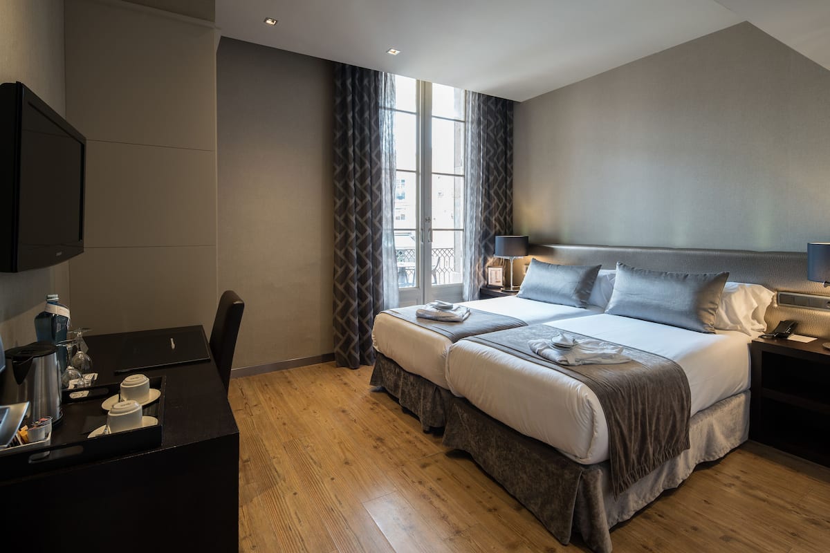 A hotel room with a bed, bedside tables, a desk with a coffee maker, and a TV.