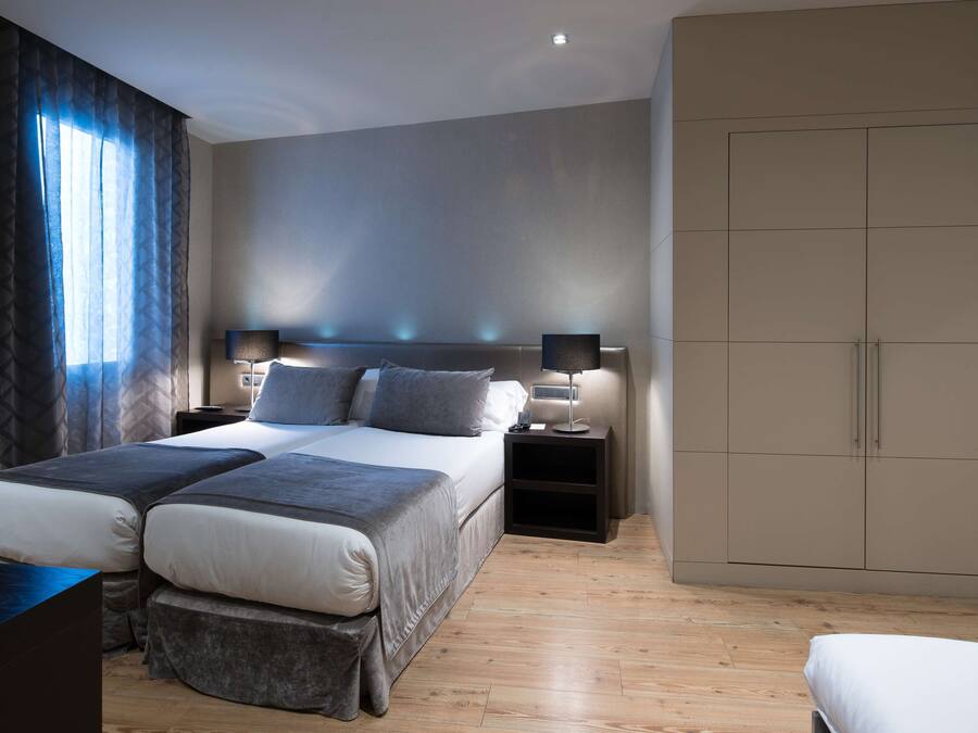 A modern bedroom with a large bed, bedside tables, and a wardrobe.