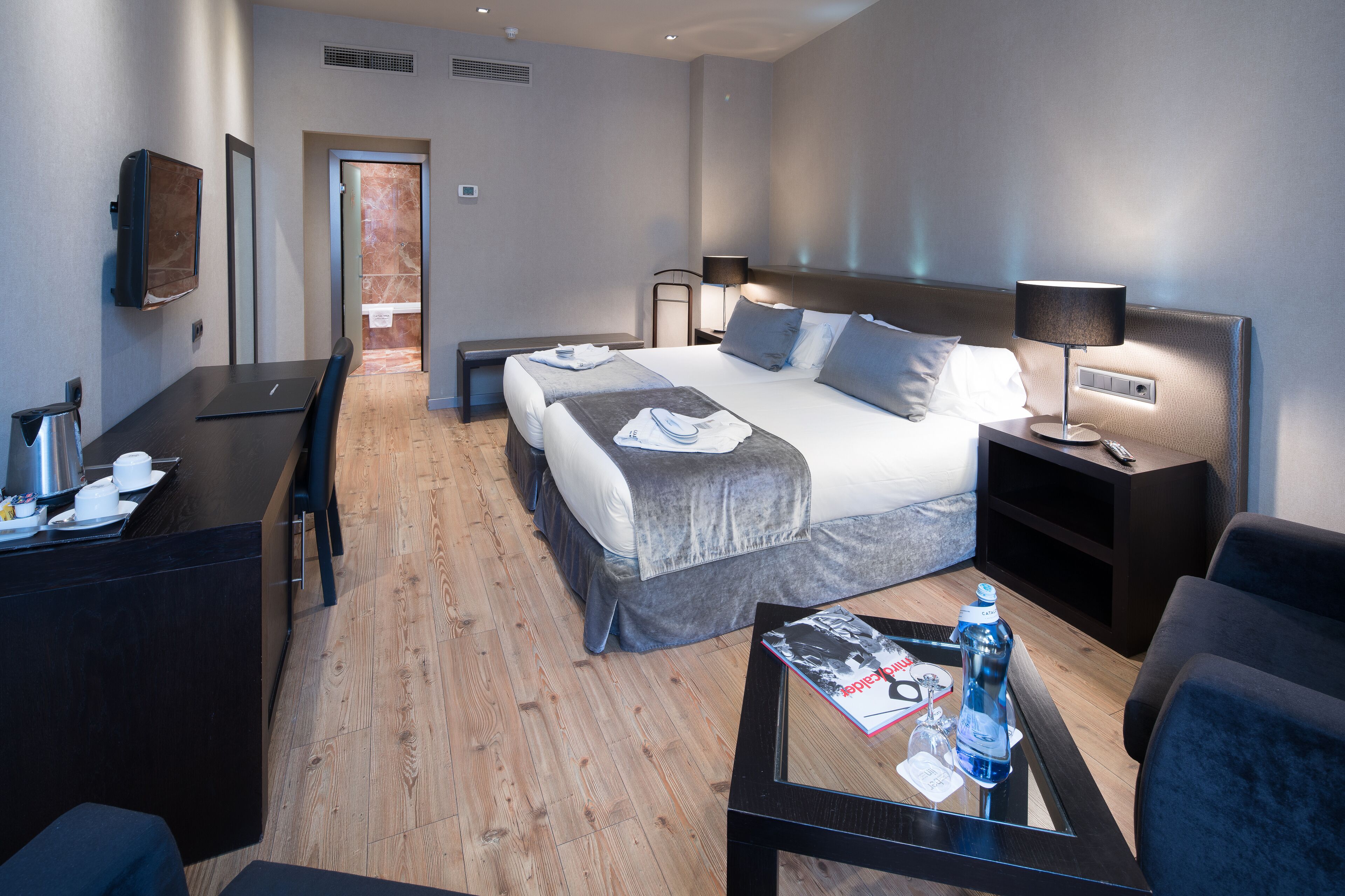 Una habitación de hotel con cama, mesitas de noche, escritorio y mesa de centro.