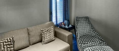A living room with a beige sofa, patterned pillows, a matching ottoman, and a side table with a tray.