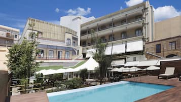 Een buitenzwembad, parasols bij het zwembad en ligstoelen