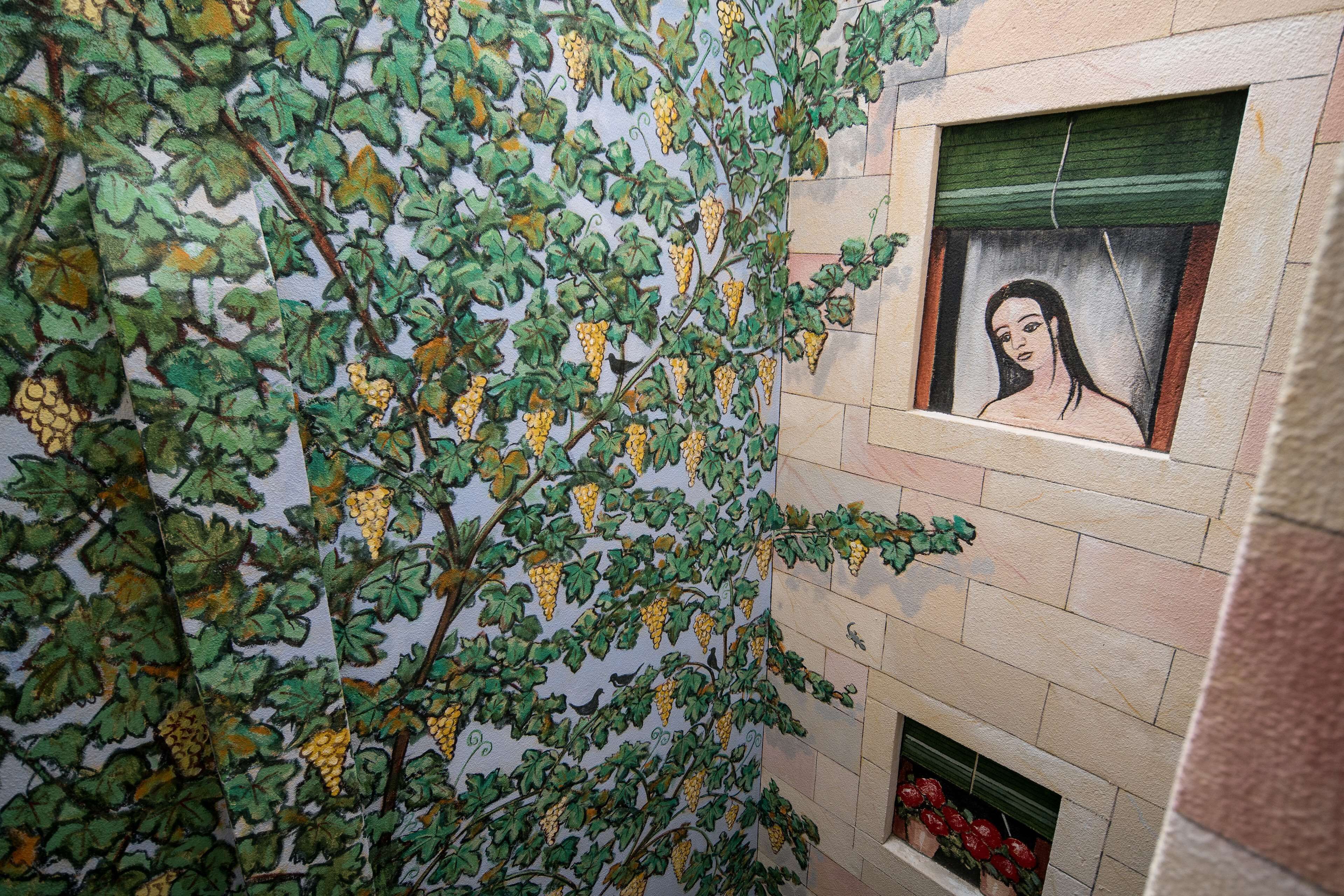 Una pared con un mural de parra y un retrato enmarcado.