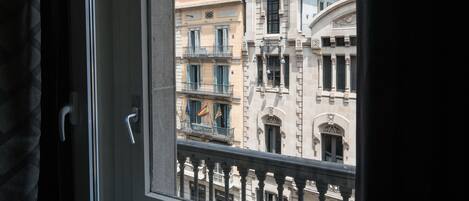 Ein Fenster mit Blick auf ein Gebäude im klassischen Stil, inklusive eines Balkons mit Flaggen.