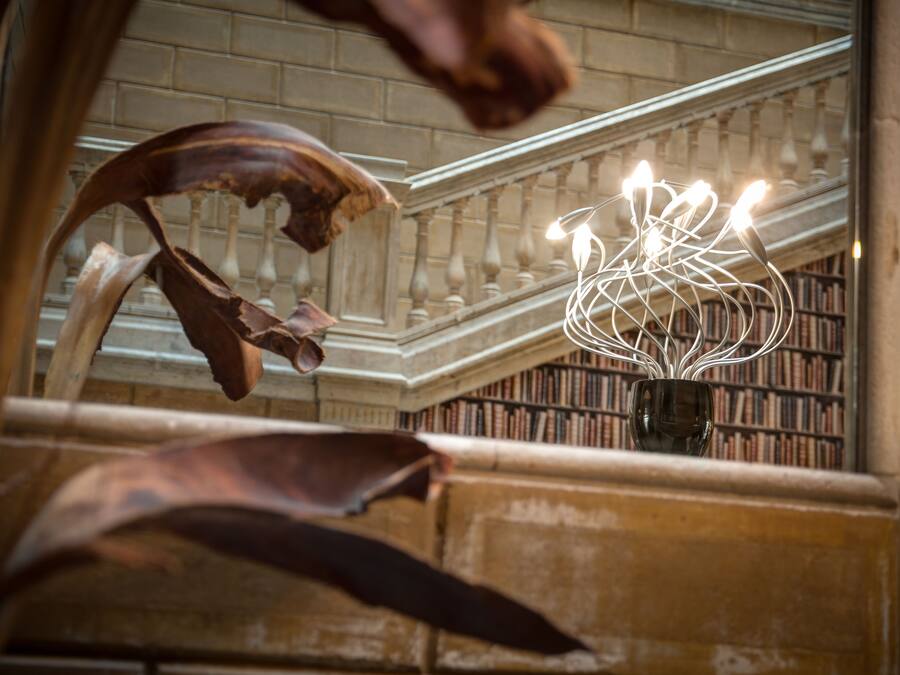 Un lustre doté de plusieurs ampoules, un mur en briques et un escalier orné de balustrades.