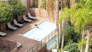 Piscina no terraço com espreguiçadeiras e vista para o verde ao redor.
