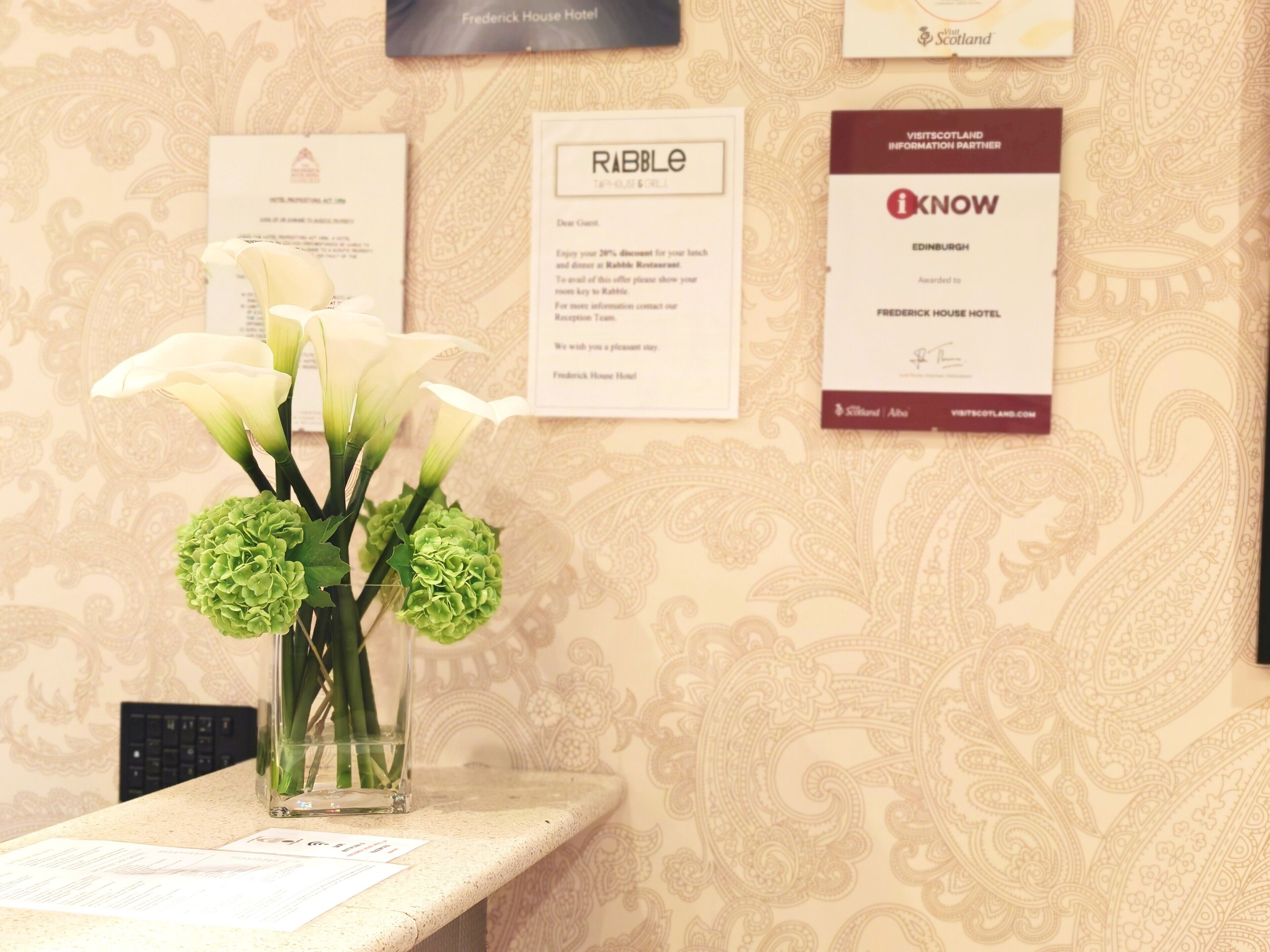 A reception desk with a vase of flowers, a menu, and informational cards on the wall.