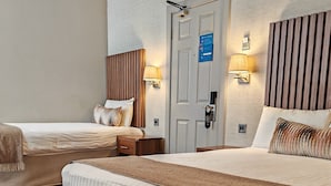 Une chambre d’hôtel avec deux lits, une moquette à motifs et des lampes fixées au mur.