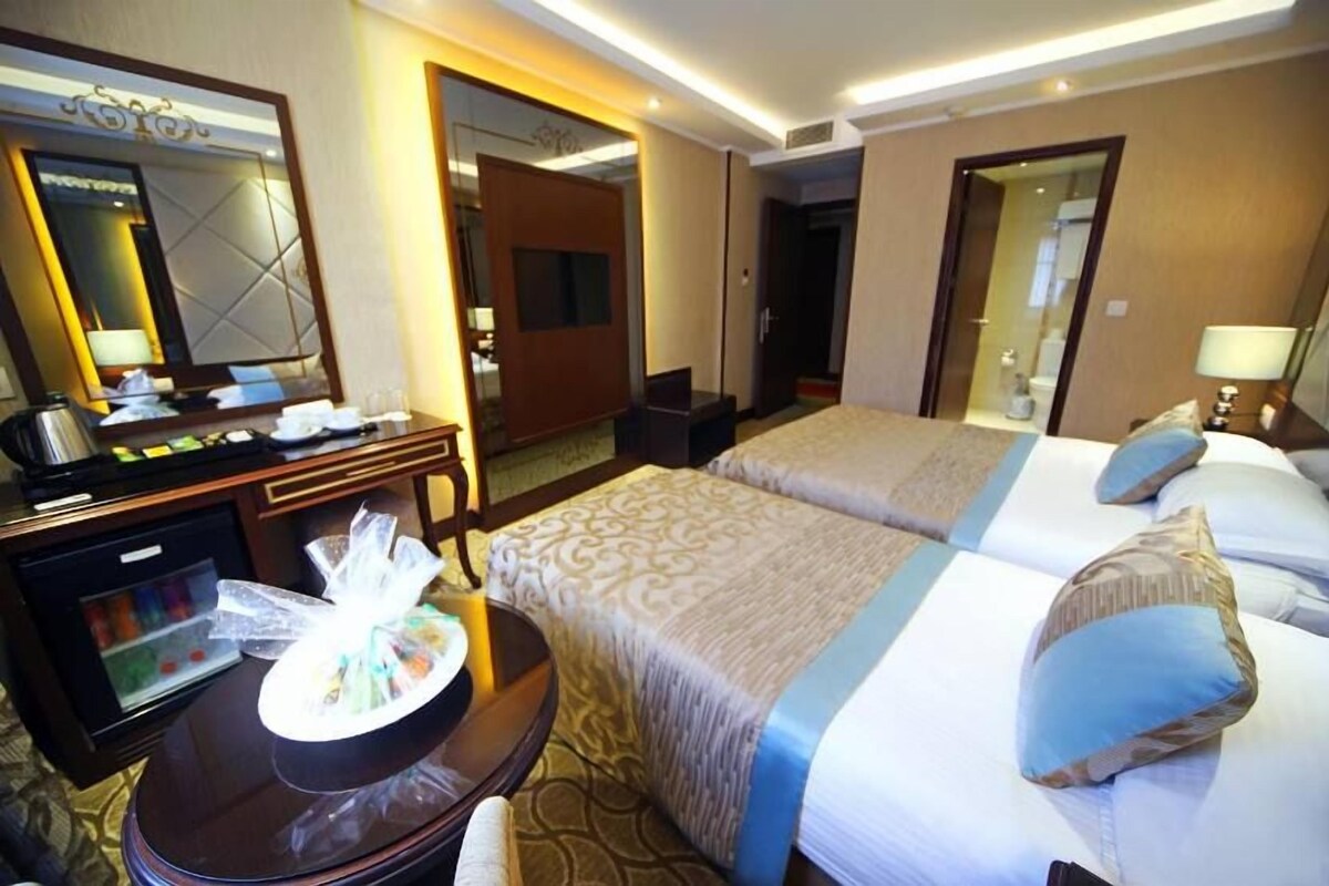 Habitació d'hotel amb dos llits, una escriptori amb un ordinador, un mirall i un minibar.