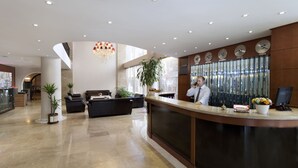 Un moderno vestíbulo de hotel con mostrador de recepción, zona de estar y ventanas amplias.
