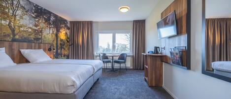 A hotel room with a bed, a desk, a chair, a TV, and a window with curtains.